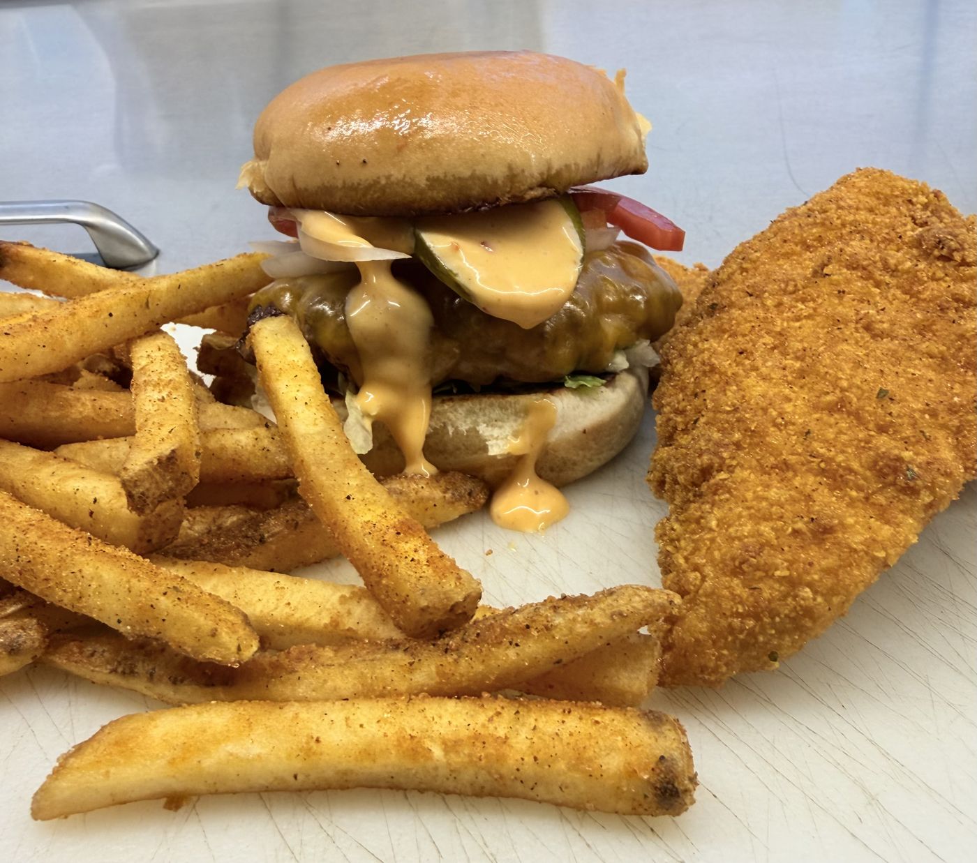 Burger with secret sauce, seasoned fries and a fried chicken tender from The Beefy Bird